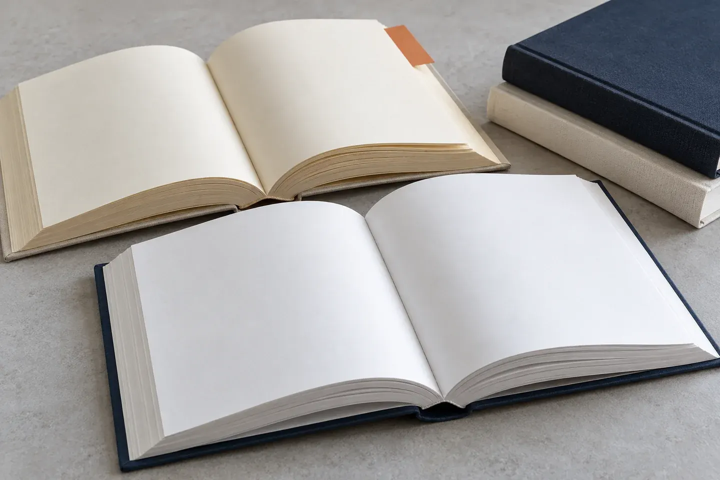 Open books with white and cream pages beside a stack of plain covered books